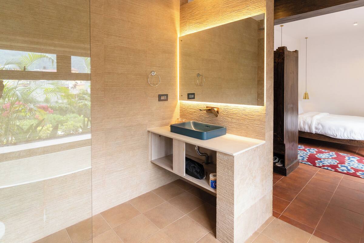 A modern bathroom with a built-in sink, a large mirror, and a view of a garden.