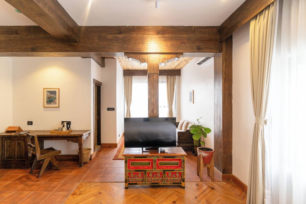 A spacious living room with a wooden ceiling, a television, a sofa, and a coffee table.