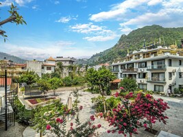 Un patio con plantas en macetas, una pérgola y vistas de edificios y colinas circundantes.