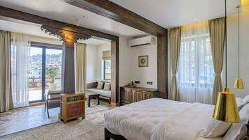 Habitación de hotel con una cama grande, un escritorio, una silla, una mesita y vistas a la ciudad.