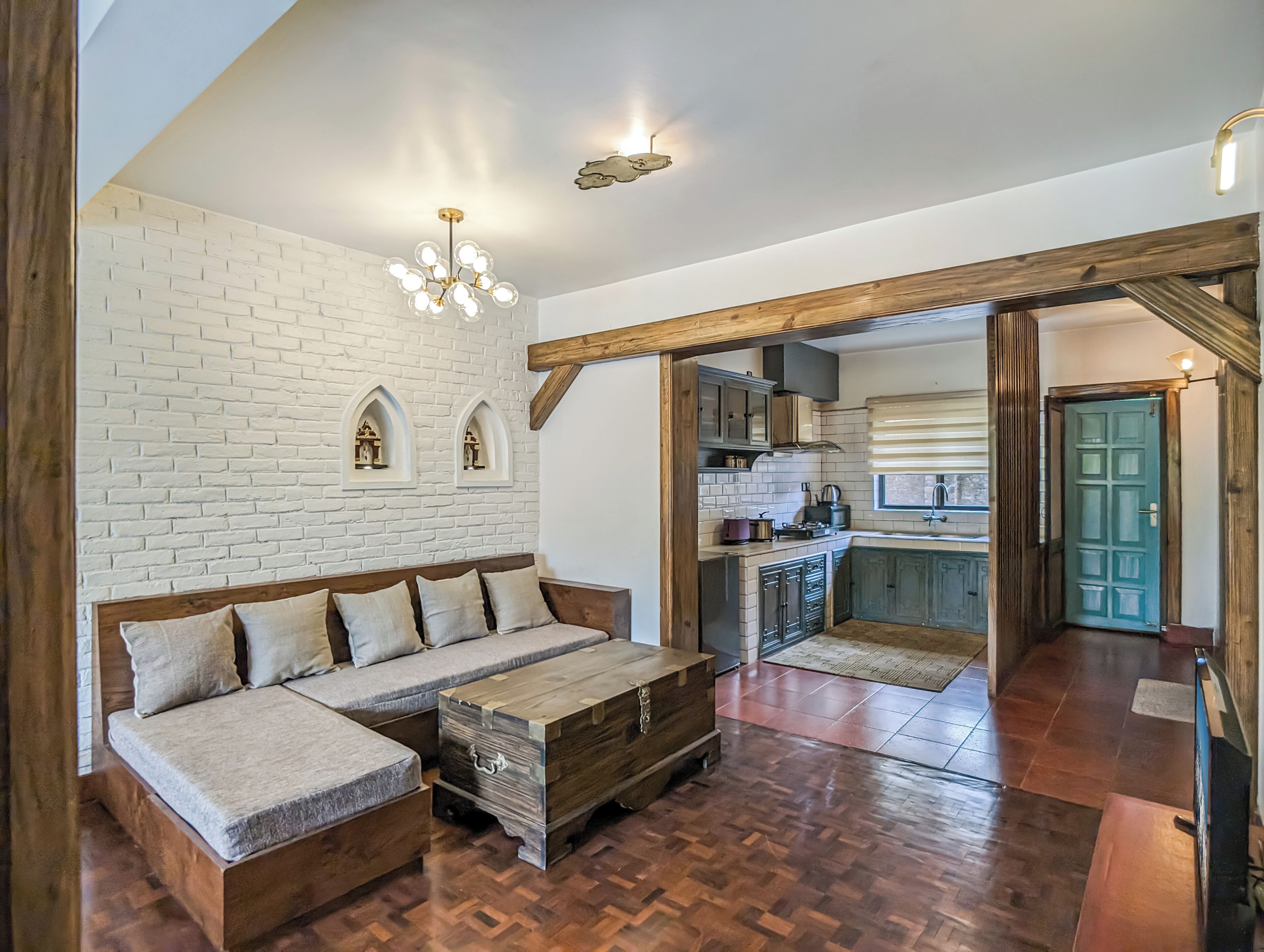 Una sala de estar acogedora con un sofá modular, una mesa de centro de madera y una pared de ladrillo con nichos en arco.