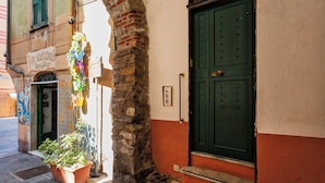 Un bâtiment avec une porte verte, une enseigne au-dessus de la porte et un pot de fleurs à l’extérieur.