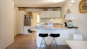 Une cuisine moderne avec des meubles blancs, un îlot central doté de tabourets et des assiettes décoratives accrochées au mur.