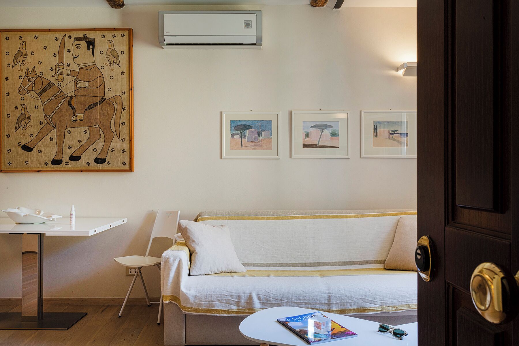 Ein Hotelzimmer mit einem Bett, einem Schreibtisch und einem Stuhl. An der Wand hängen drei gerahmte Bilder.
