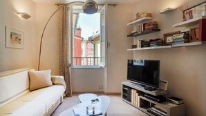 Un salon avec un canapé, une table basse, un téléviseur et des étagères à livres.