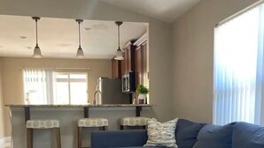 A modern living room with a sectional sofa, a kitchen area with a microwave, and a dining bar with stools. - Private pool-Comfy home- 8 guest

 (Davenport)