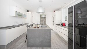 Een moderne keuken met een centraal eiland, witte kasten en een zwarte koelkast.