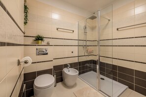 Un baño moderno con inodoro, bidé y ducha con mampara de vidrio.