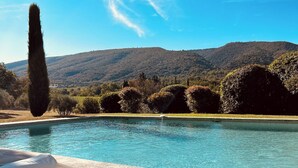 Un área de descanso junto a la piscina con vistas a una cadena montañosa.