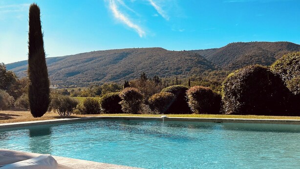 Un área de descanso junto a la piscina con vistas a una cadena montañosa.