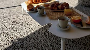 Un desayuno con croissants, jugo de naranja y una taza sobre una mesa con un mantel estampado.