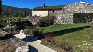 Una casa de piedra con un muro de piedra y un pequeño jardín con un sendero.