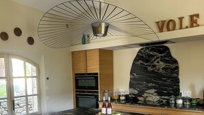 Una cocina moderna con una isla grande, armarios de madera, salpicadero de piedra y un ventilador de techo.