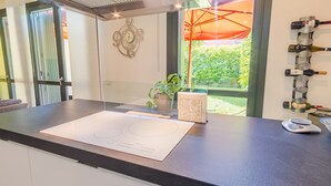 A modern kitchen with a large island, a potted plant, and a wine rack. - Lugana Lovers - Italian Homing (Sirmione)