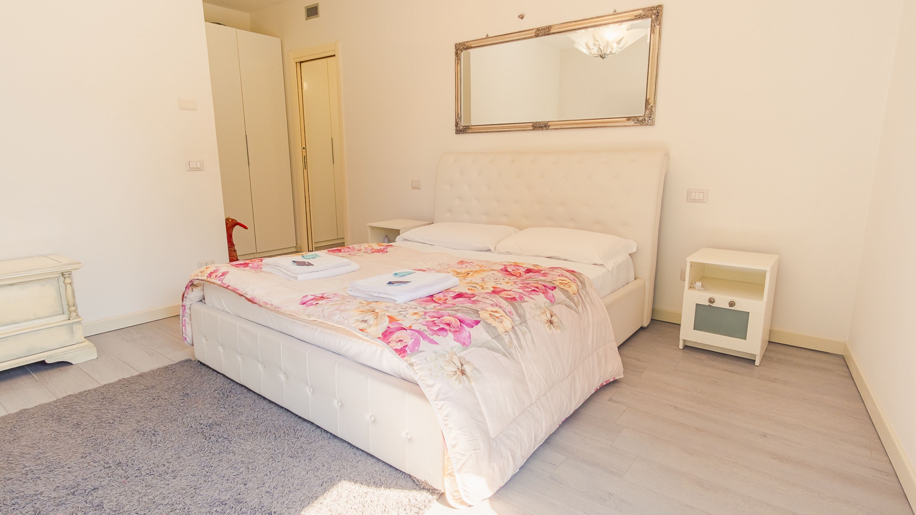 A bedroom with a bed, a nightstand, a dresser, and a mirror.