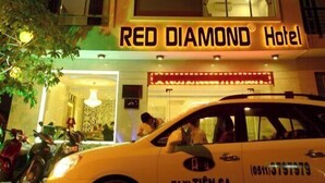 Un immeuble à plusieurs étages, avec des fenêtres illuminées et une enseigne indiquant « Hôtel RED DIAMOND ».