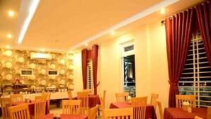 Un espace repas comprenant plusieurs tables et chaises, un mur décoré de motifs et une fenêtre avec des rideaux.