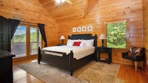 A wooden cabin bedroom with a bed, nightstands, a chair, and a ceiling fan. - Mountain Retreat Hot Tub & Game Room Pets Friendly (Mineral Bluff)