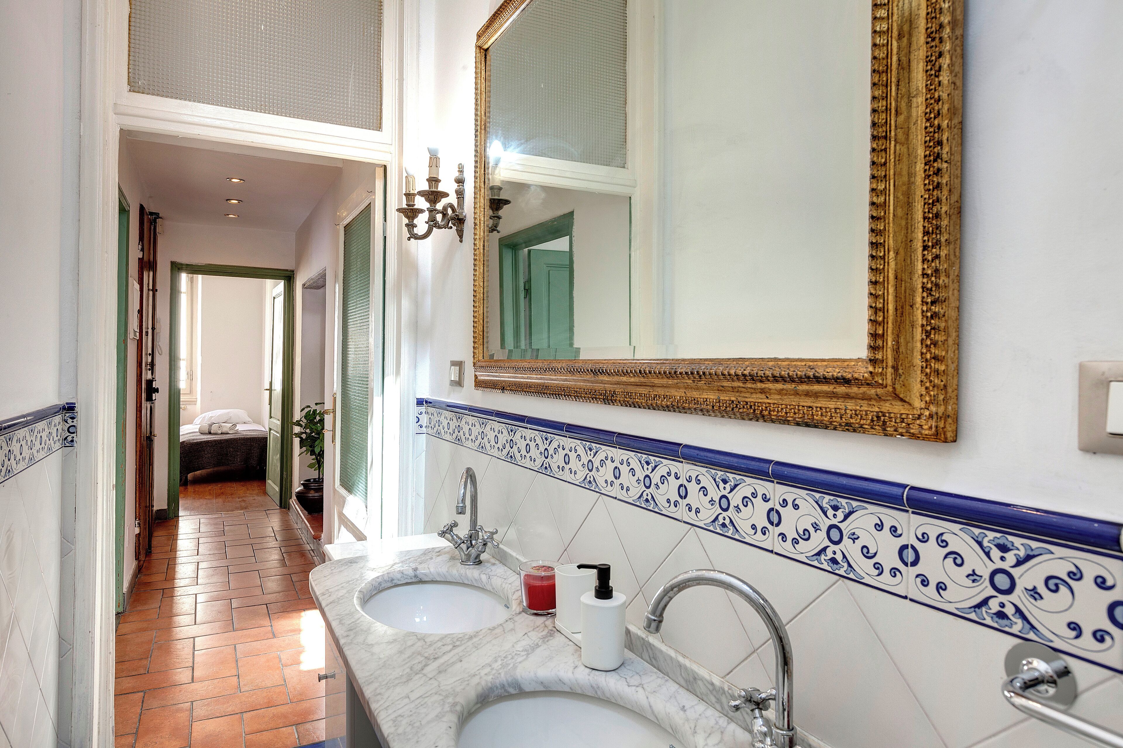 A bathroom with two sinks, a large mirror, and a decorative tile border.