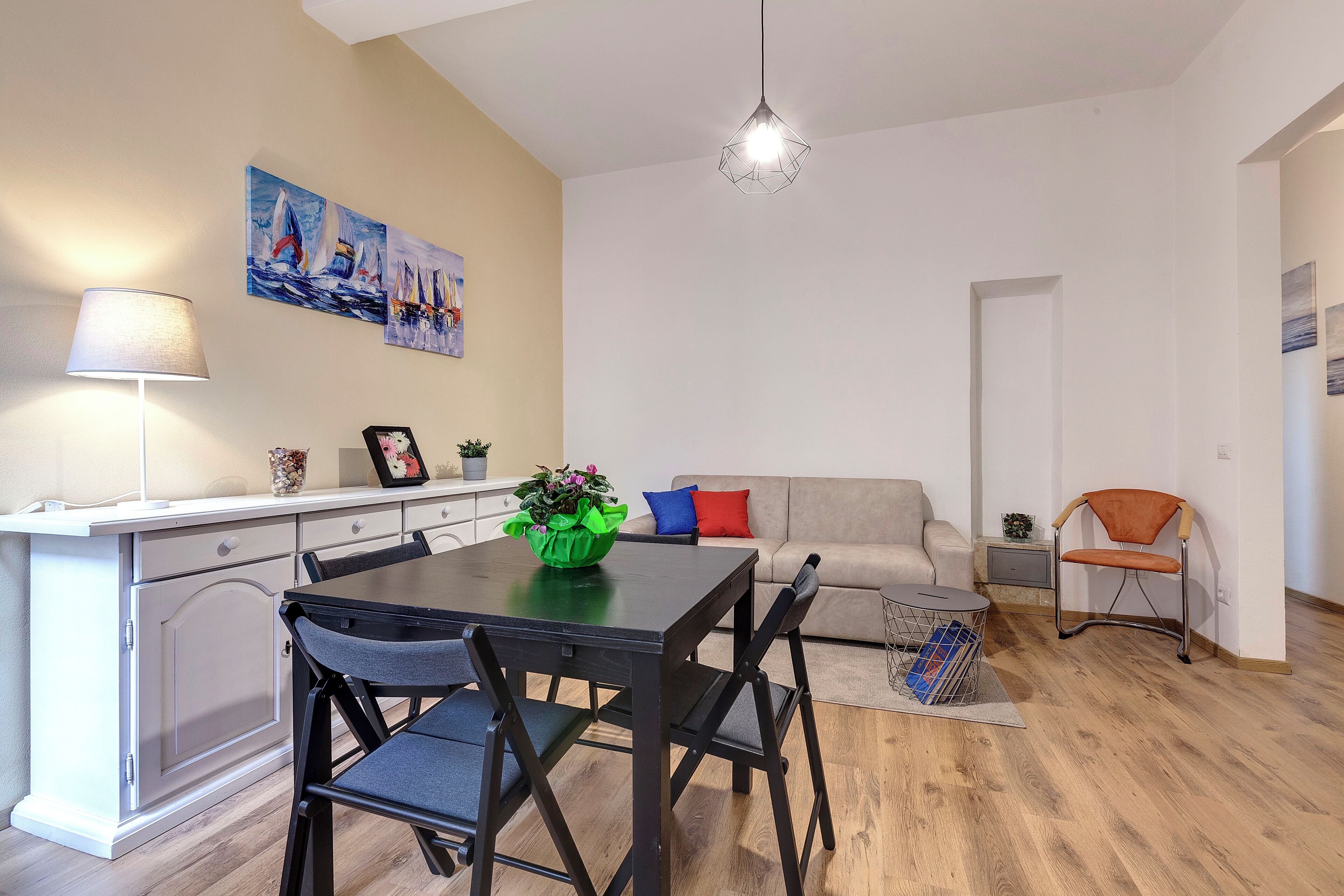 Una sala moderna con comedor, un sofá, una silla y una lámpara.