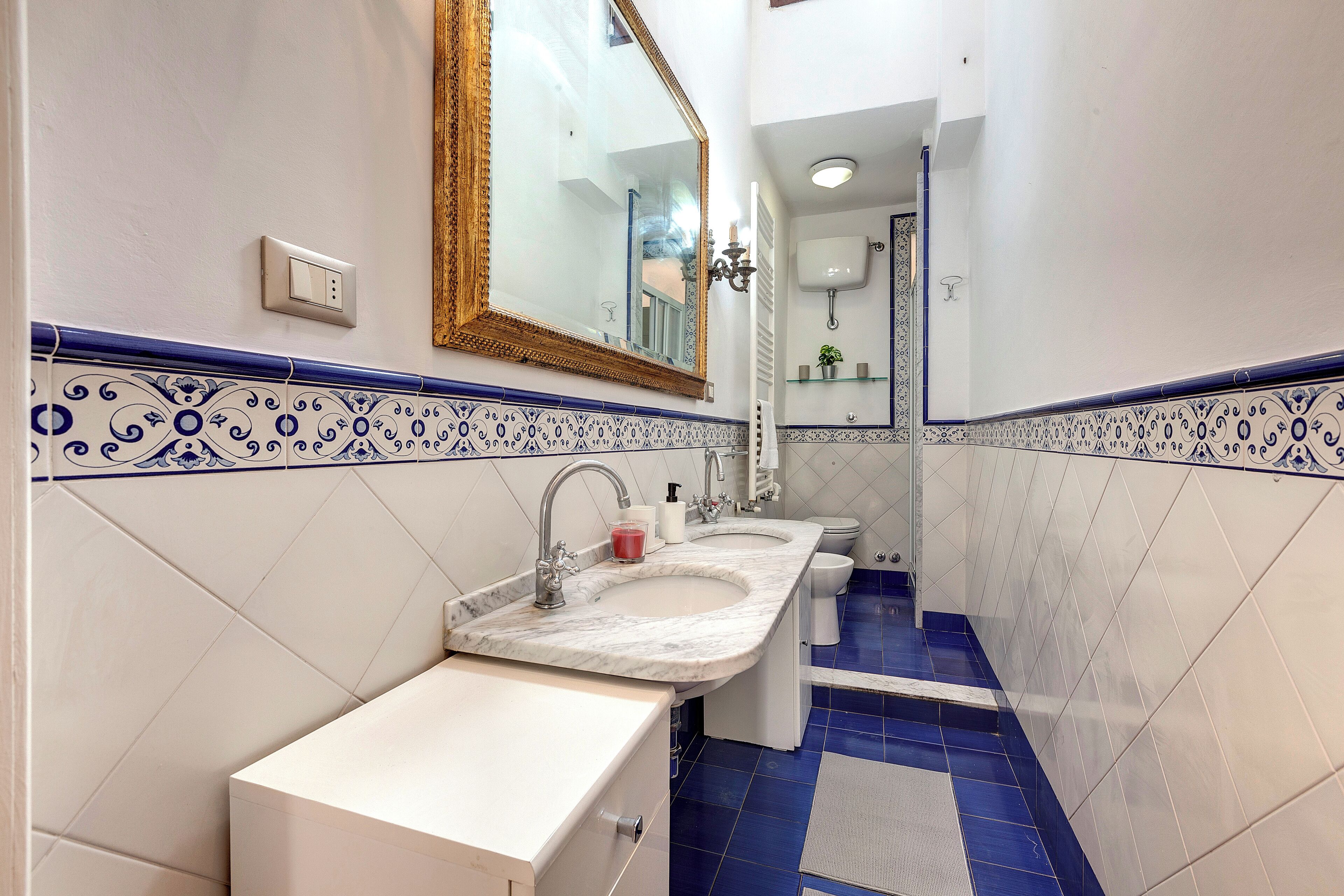A bathroom with two sinks, a large mirror, and blue decorative tiles.