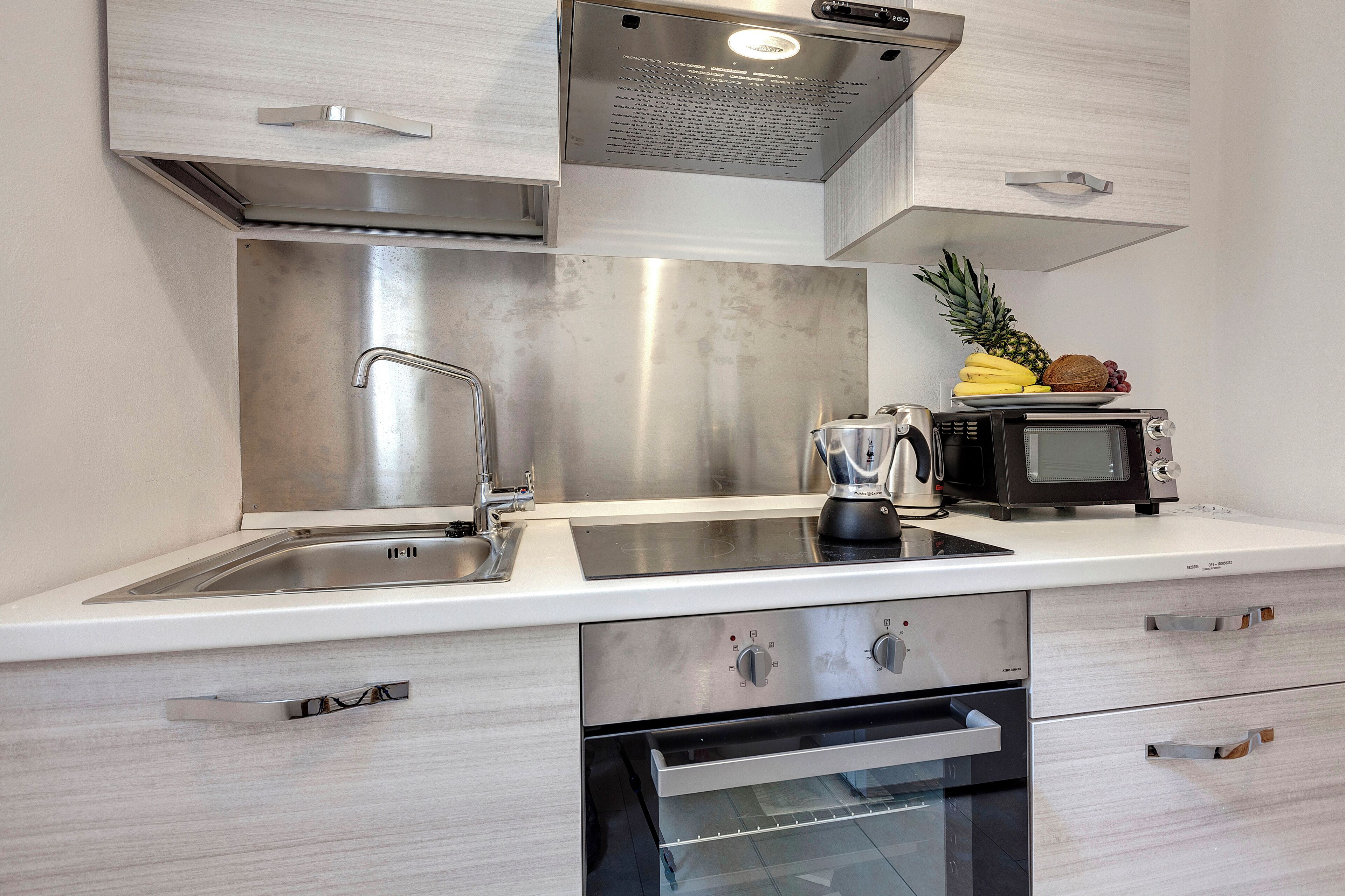 Una cocina moderna con electrodomésticos de acero inoxidable, horno empotrado y microondas en la encimera.
