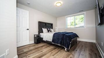 A bedroom with a bed, a window, a door, and a ceiling light.