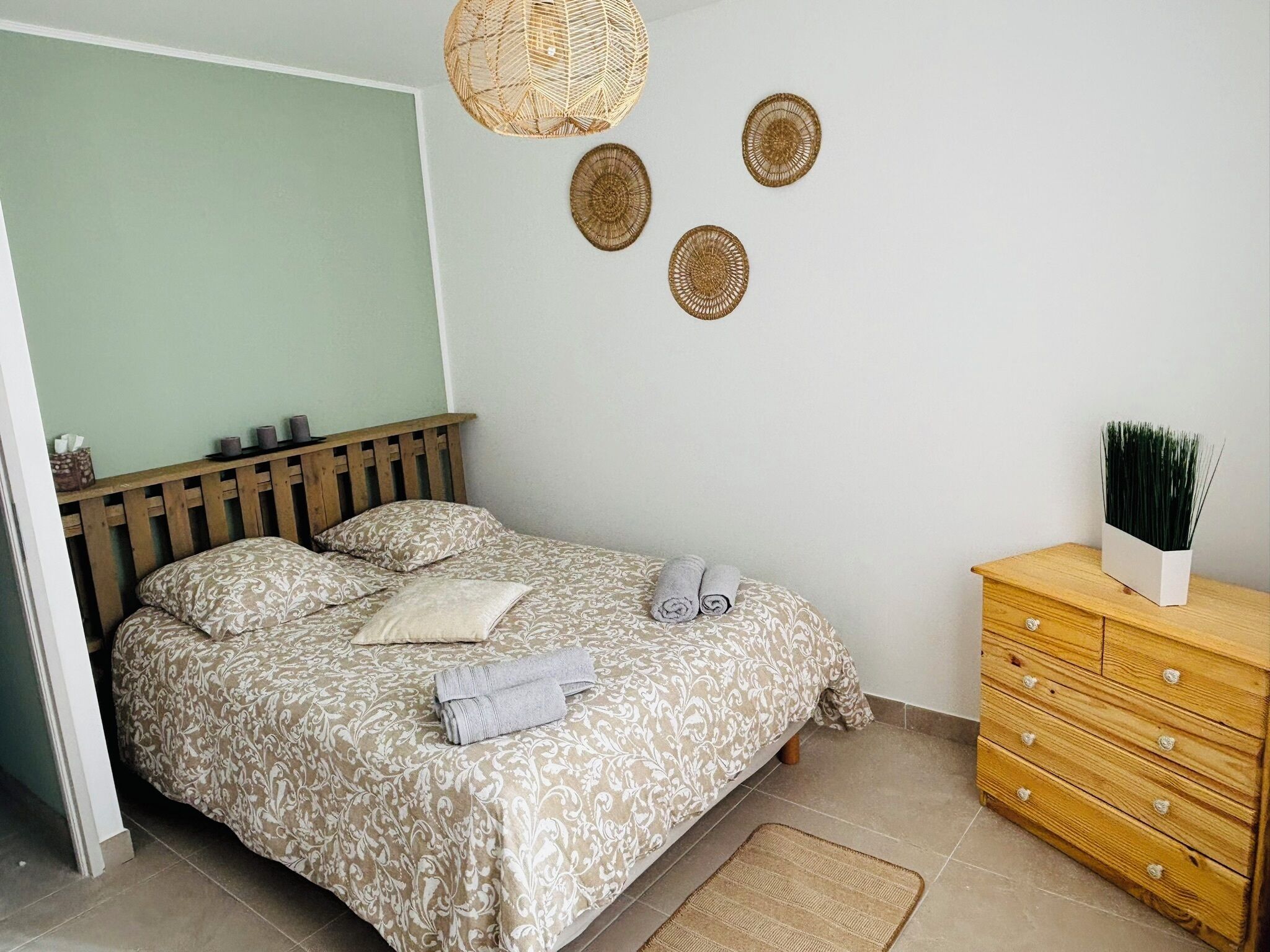 Un dormitorio con una cama, un aparador de madera y adornos en la pared.