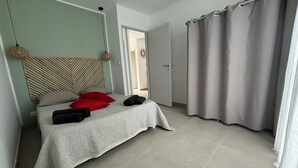 A bedroom with a bed, a headboard, a door, and a curtain. - Maison au Calme Avec Piscine (SAINT MICHEL D'EUZET)