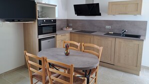 Una cocina moderna con zona de comedor, horno empotrado, microondas y un televisor de pantalla plana montado en la pared.