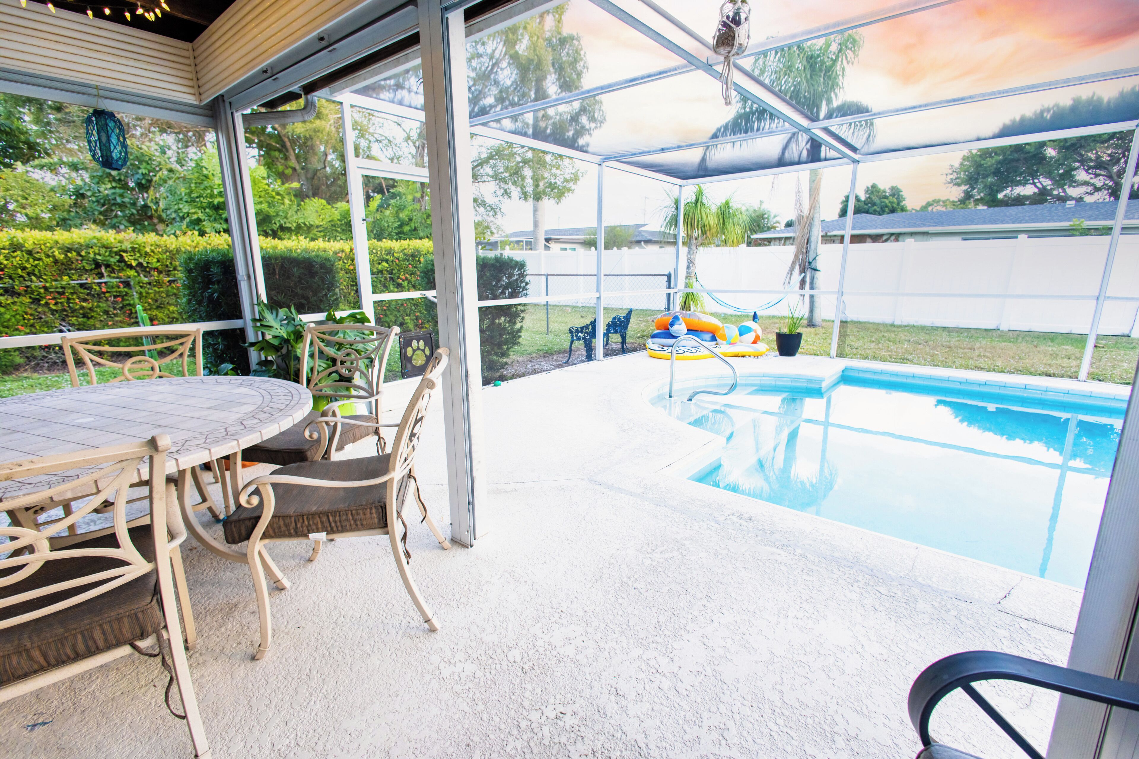 Uma área de varanda coberta com piscina, móveis de exterior e vista para o quintal.