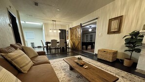 Una sala de estar con un sofá marrón, una mesa de centro de madera y una alfombra estampada.
