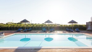 A swimming pool with lounge chairs and umbrellas.