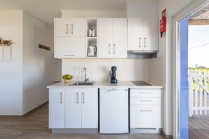 Una cocina moderna con armarios blancos, lavavajillas integrado y cafetera.