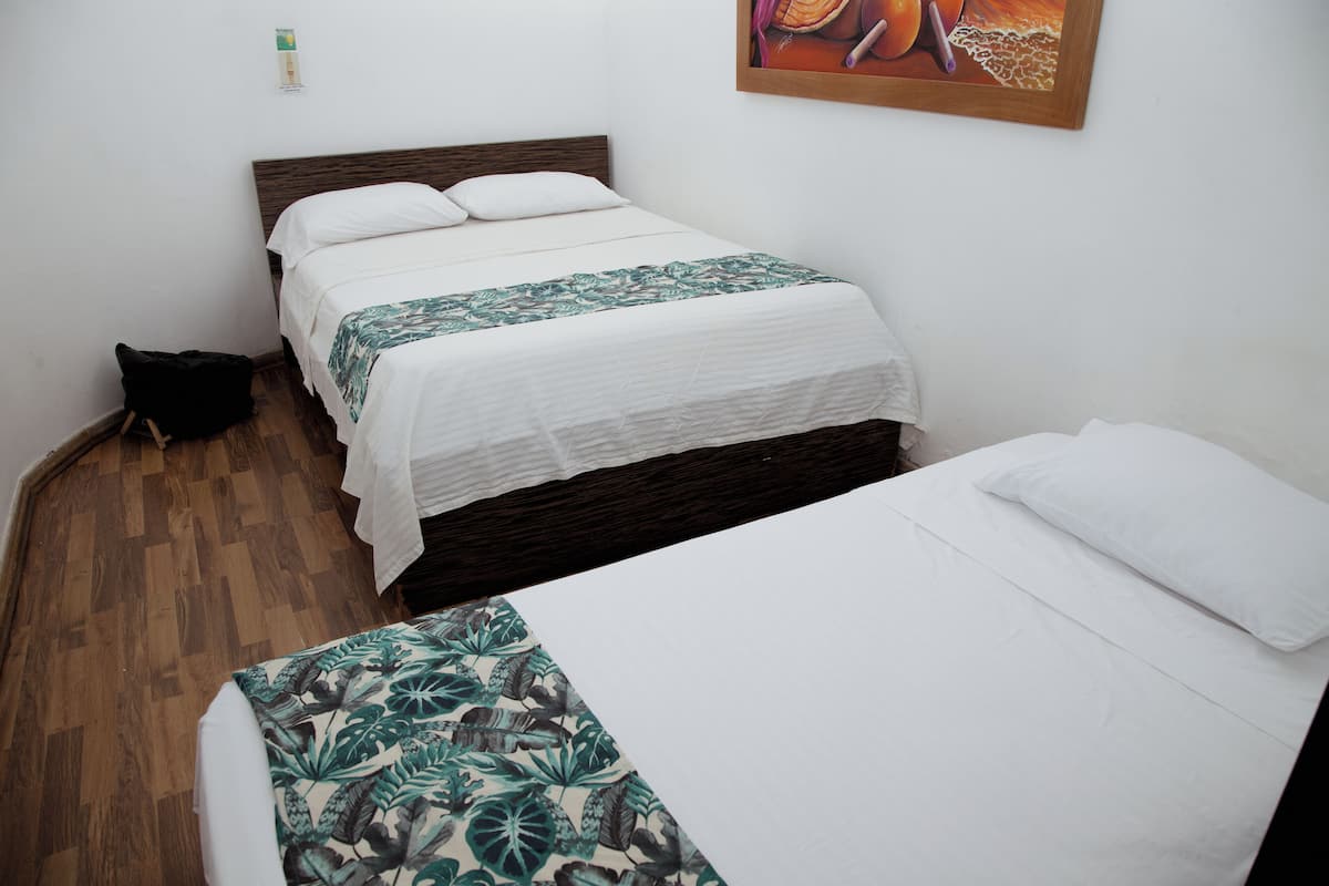 Quarto com duas camas, piso de madeira e uma pintura na parede.