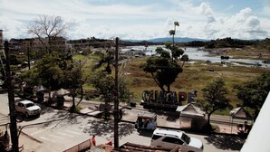 A view of a river with boats, a bridge, and a road with vehicles. - Hotel Portal Guatapé  (Guatapé)