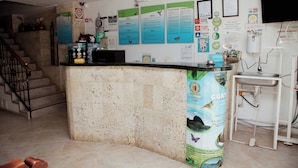 A reception area with a stone counter, a water dispenser, and various informational posters on the wall. - Hotel Portal Guatapé  (Guatapé)