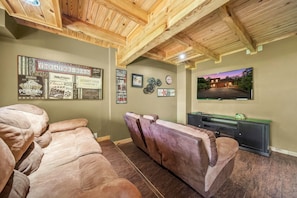 A room with a wooden ceiling, a large poster of a theater, and a reclining chair. - Pigeon Forge I Hot tub I Theatre I Walk to Parkway (Pigeon Forge)