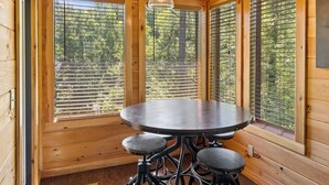 A wooden interior with a round table and stools, large windows with blinds, and a hanging light fixture. - Pigeon Forge I Hot tub I Theatre I Walk to Parkway (Pigeon Forge)