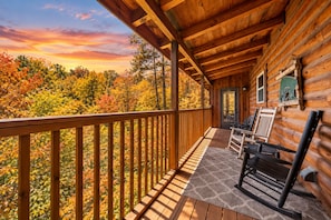 A wooden cabin with a balcony overlooking a forested area during autumn. - Pigeon Forge I Hot tub I Theatre I Walk to Parkway (Pigeon Forge)