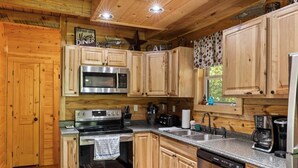 Une cuisine de style rustique, avec des éléments en bois, comprenant une cuisinière, un four à micro-ondes, un évier et un lave-vaisselle.
