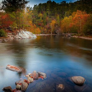 A calm river with rocks and autumn foliage in the background. - Pigeon Forge I Hot tub I Theatre I Walk to Parkway (Pigeon Forge)