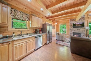 A wooden cabin interior with a kitchen, dining area, and a fireplace. - Pigeon Forge I Hot tub I Theatre I Walk to Parkway (Pigeon Forge)