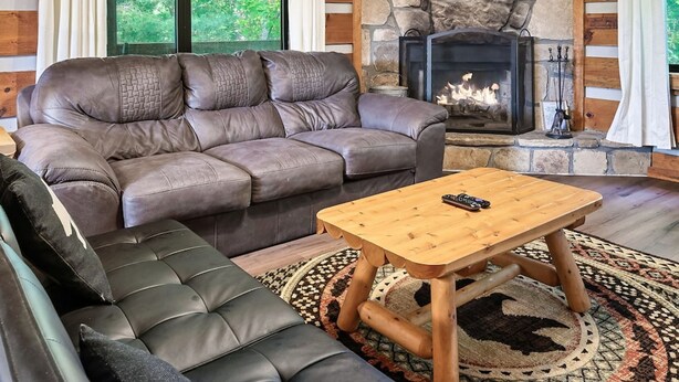 A cozy living room with a stone fireplace, leather sofas, and a wooden coffee table. - Views I Between Pigeon Forge Gatlinburg I Firepit (Sevierville)