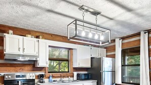 Une cuisine moderne avec des meubles blancs, des appareils en acier inoxydable et une table à manger en bois, accompagnée de chaises.
