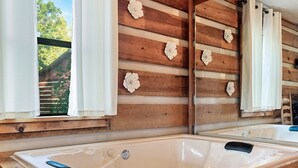 Une cabane en bois avec une grande baignoire, des murs en bois et une fenêtre avec des rideaux.