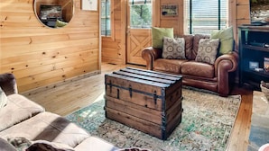 A cozy cabin interior with a wooden ceiling, a leather sofa, a round mirror, a clock, and a rustic chest. - Minutes From Parkway I Private I Views I Hot tub (Pigeon Forge)