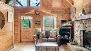 A cozy log cabin interior with a leather sofa, a stone fireplace, and wooden walls. - Minutes From Parkway I Private I Views I Hot tub (Pigeon Forge)