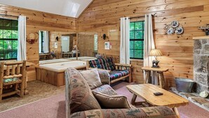 L’intérieur chaleureux d’un chalet, avec un revêtement mural en bois, un canapé, une table et une cheminée.