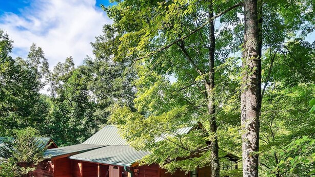 Une cabane avec une véranda, un foyer et un banc.